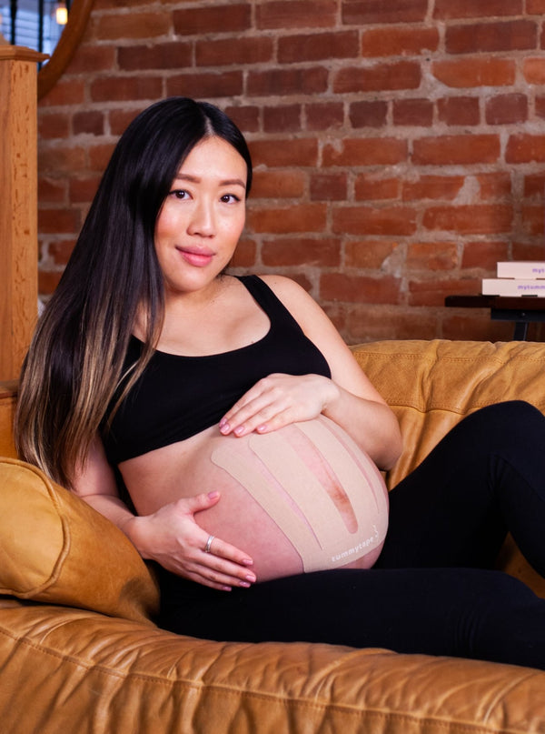 pregnant woman relaxing with belly supported by beige pregnancy tape