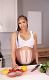 pregnant woman cooking with belly supported by blush sensitive skin kinesiology tape for pregnancy