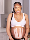 pregnant lady laughing with baby belly taped with blush kinesiology tape