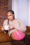 pregnant woman drinking tea with belly supported by pink pregnancy tape