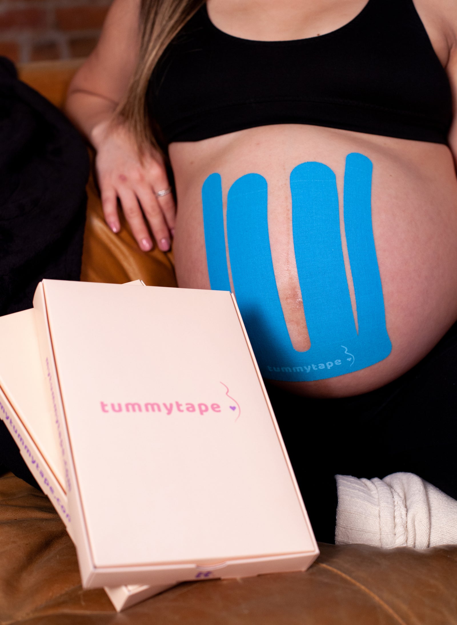 pregnant woman wearing blue kinesiology tape beside tummytape packaging