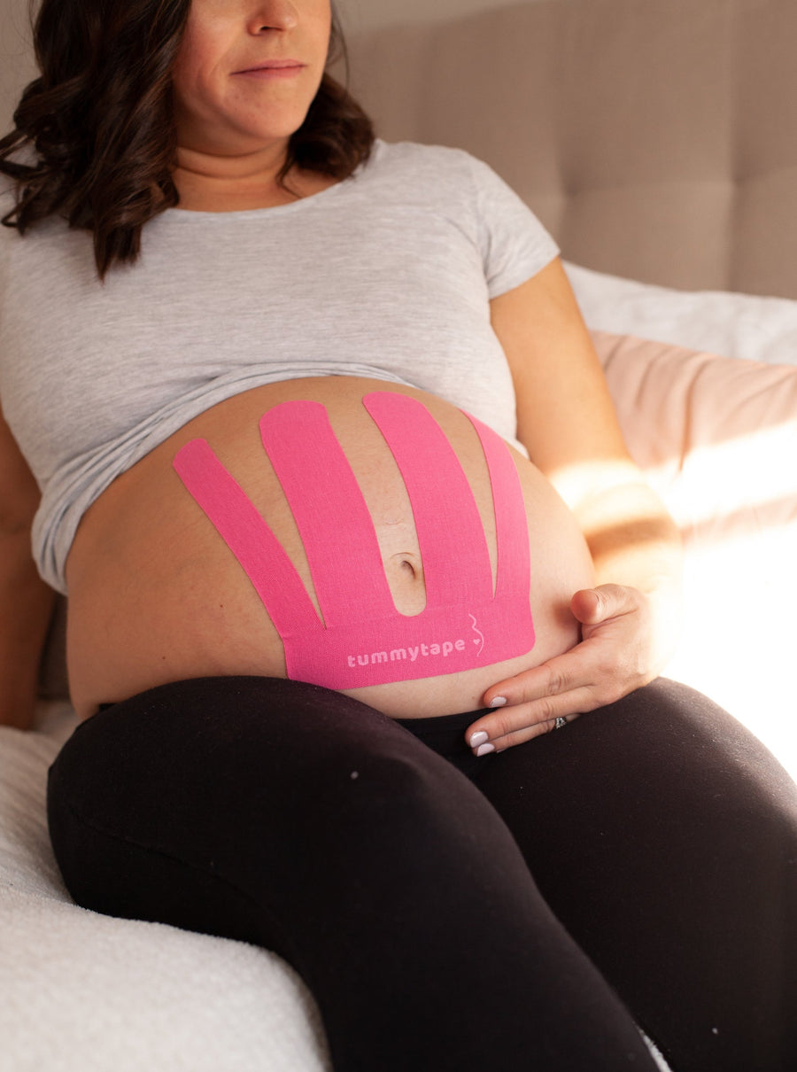 mom relaxing while wearing pink pregnancy belly tape