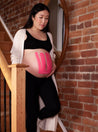 pregnant woman walking down stairs with belly supported by pink kinesiology tape. Caption reads "For sensitive skin"